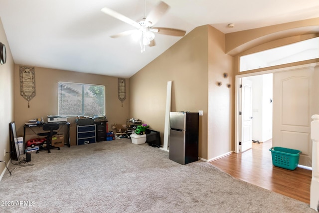 carpeted office with lofted ceiling, ceiling fan, and wood finished floors