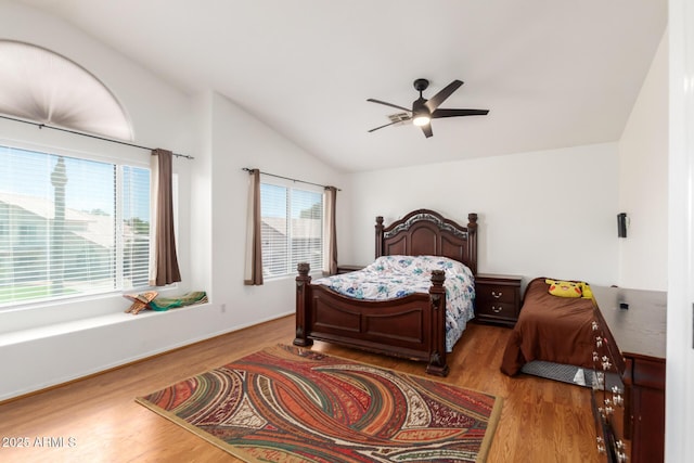 bedroom featuring a ceiling fan, multiple windows, vaulted ceiling, and wood finished floors