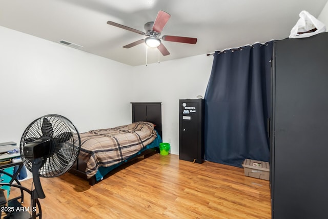 bedroom featuring light wood finished floors, visible vents, and a ceiling fan