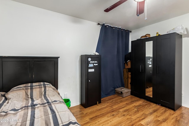 bedroom featuring light wood finished floors, a ceiling fan, and baseboards