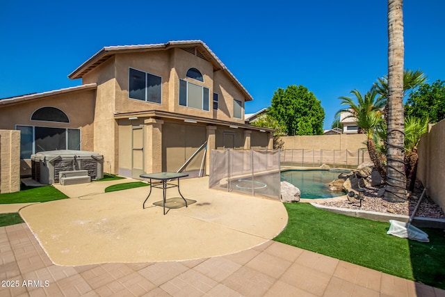 back of house featuring a hot tub, a fenced in pool, a patio, a fenced backyard, and stucco siding