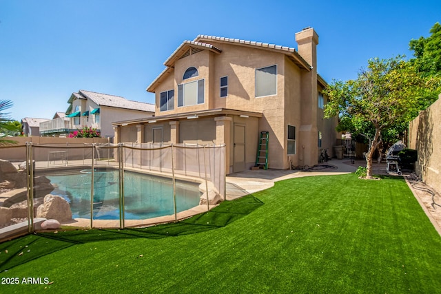 rear view of house featuring a patio, a yard, a chimney, stucco siding, and a fenced backyard