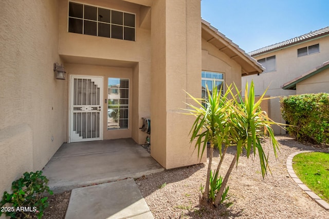 view of exterior entry with a patio area and stucco siding