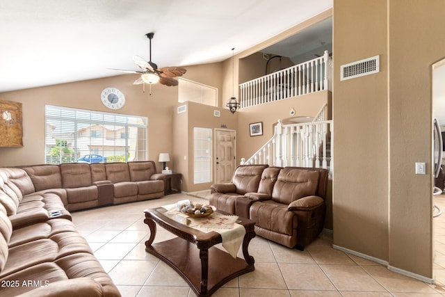 living area featuring light tile patterned floors, visible vents, ceiling fan, stairs, and high vaulted ceiling