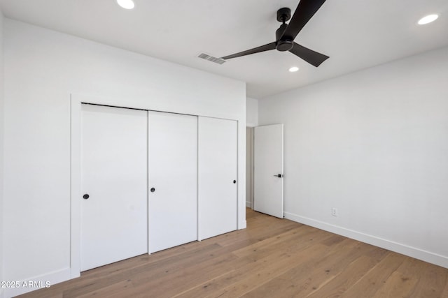 unfurnished bedroom with ceiling fan, light wood-type flooring, and a closet