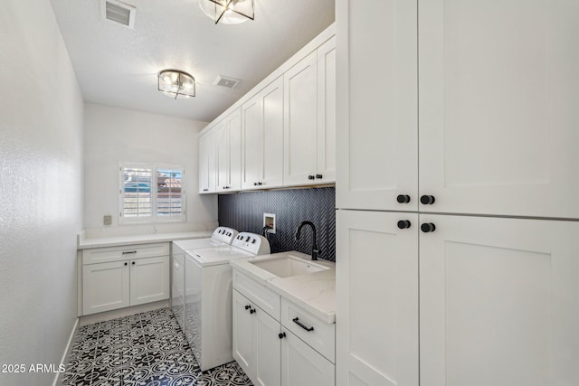 laundry room with sink, light tile patterned floors, cabinets, a textured ceiling, and washing machine and clothes dryer