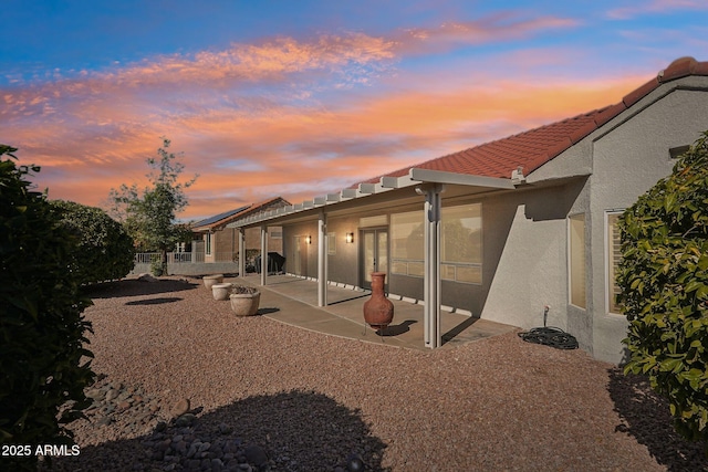 back house at dusk featuring a patio