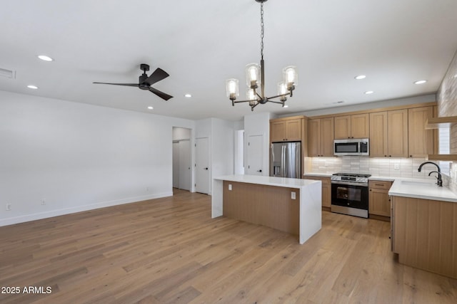 kitchen featuring sink, appliances with stainless steel finishes, hanging light fixtures, backsplash, and a kitchen island