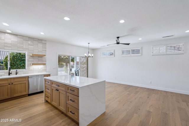 kitchen featuring sink, backsplash, a wealth of natural light, stainless steel dishwasher, and light wood-type flooring