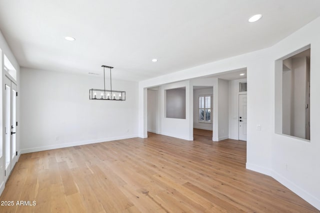 unfurnished room with an inviting chandelier and light hardwood / wood-style flooring