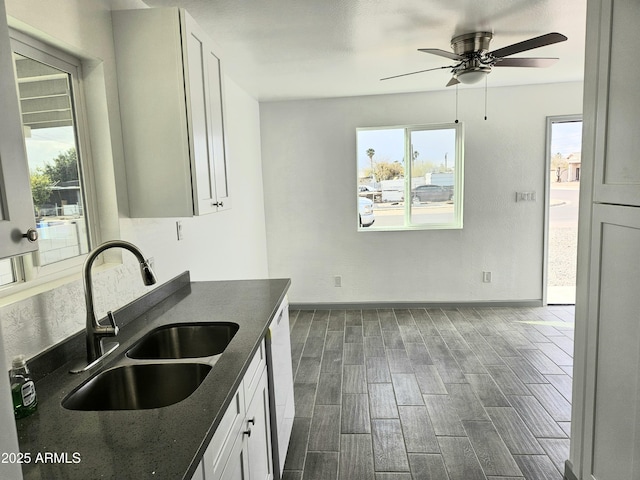 kitchen featuring sink, dark stone countertops, white cabinets, ceiling fan, and white dishwasher