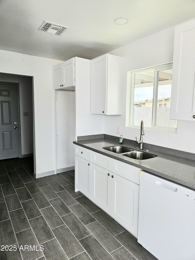 kitchen featuring dishwasher, sink, and white cabinets