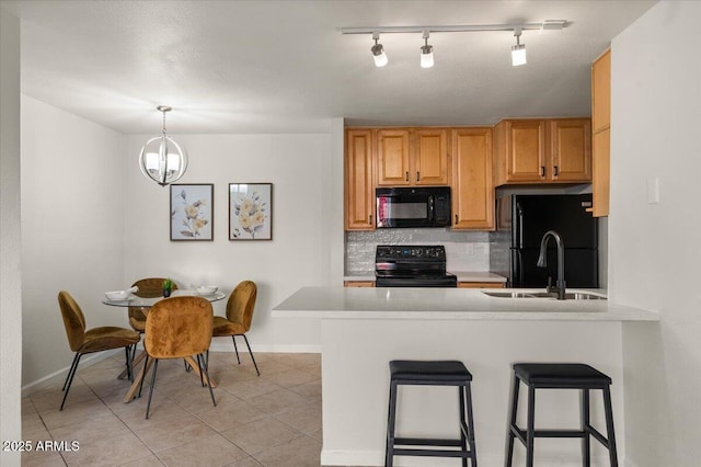 kitchen with light tile patterned floors, tasteful backsplash, black appliances, decorative light fixtures, and kitchen peninsula