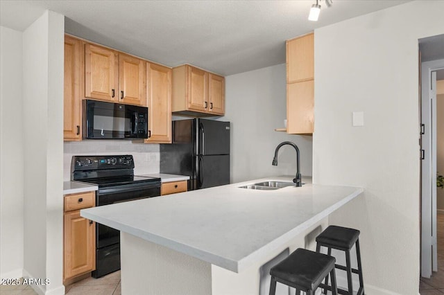 kitchen with sink, a breakfast bar area, kitchen peninsula, decorative backsplash, and black appliances