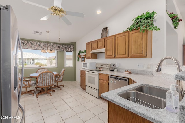 kitchen featuring light tile patterned flooring, vaulted ceiling, sink, light stone counters, and appliances with stainless steel finishes