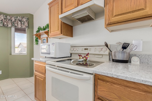 kitchen featuring light stone countertops, light tile patterned floors, and white appliances