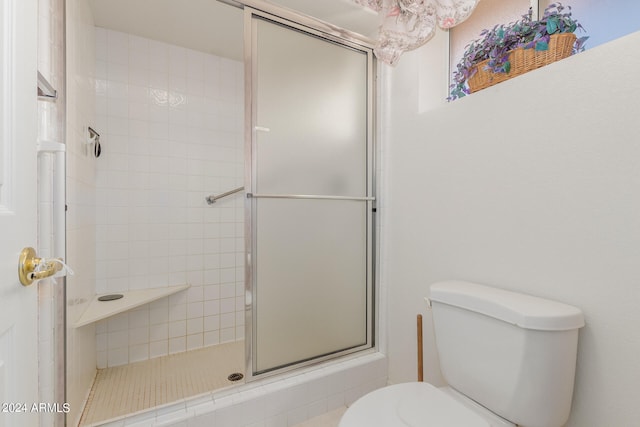 bathroom featuring a shower with shower door and toilet