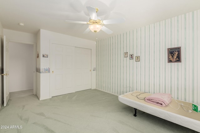 unfurnished bedroom featuring light carpet, a closet, and ceiling fan