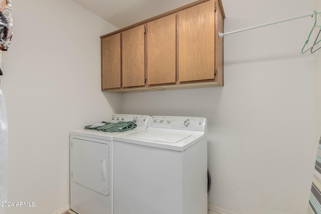 washroom with washing machine and clothes dryer and cabinets