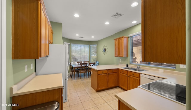 kitchen featuring light tile patterned floors, white appliances, sink, and kitchen peninsula