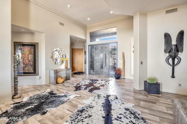 foyer entrance featuring crown molding and a high ceiling