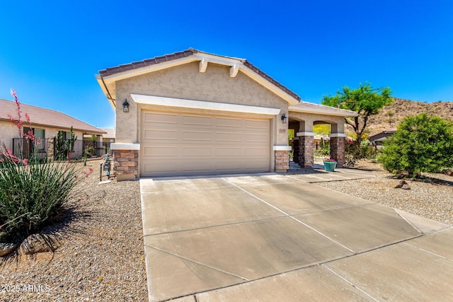 view of front of home with an attached garage, driveway, stone siding, and stucco siding