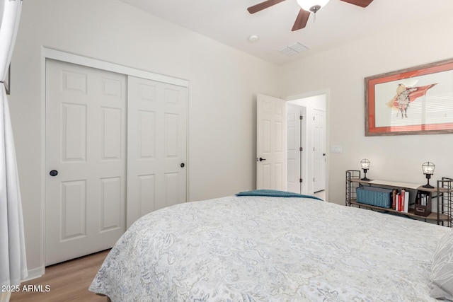 bedroom featuring a closet, visible vents, a ceiling fan, and wood finished floors