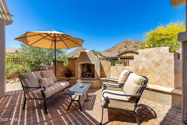 view of patio with a mountain view, fence, and an outdoor living space with a fireplace