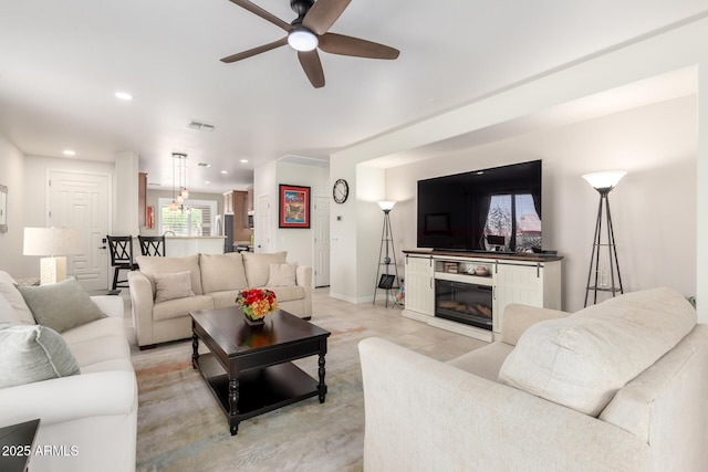 living area with recessed lighting, ceiling fan, a glass covered fireplace, visible vents, and baseboards