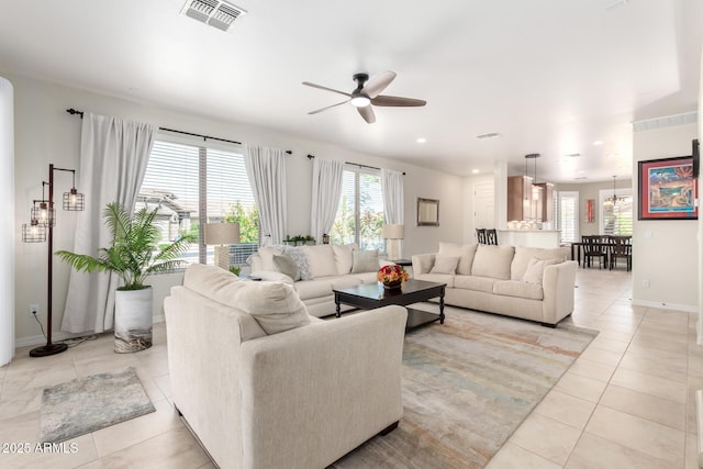 living area with baseboards, visible vents, light tile patterned floors, and a ceiling fan