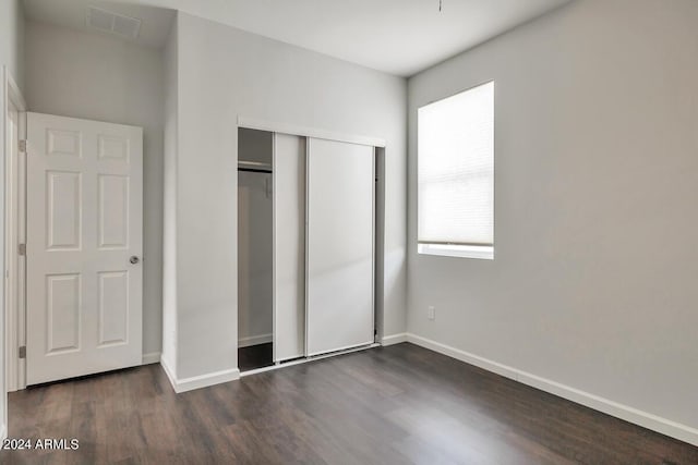 unfurnished bedroom featuring dark hardwood / wood-style floors and a closet