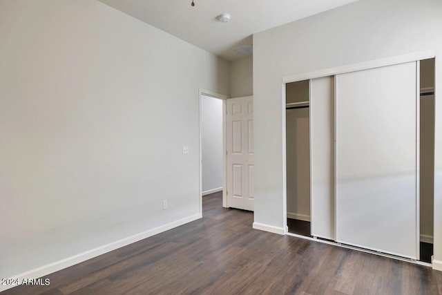 unfurnished bedroom with dark hardwood / wood-style floors and a closet