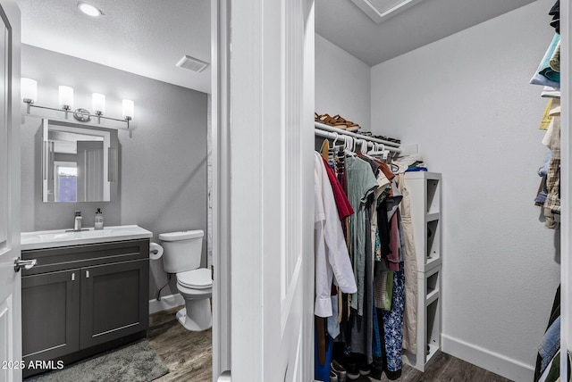 4502 W Continental Dr, Glendale, AZ 85308 - bathroom with wood finished floors, a spacious closet, vanity, and toilet