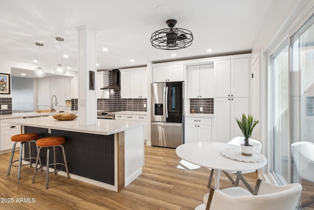 kitchen with white cabinets, appliances with stainless steel finishes, wall chimney exhaust hood, and tasteful backsplash