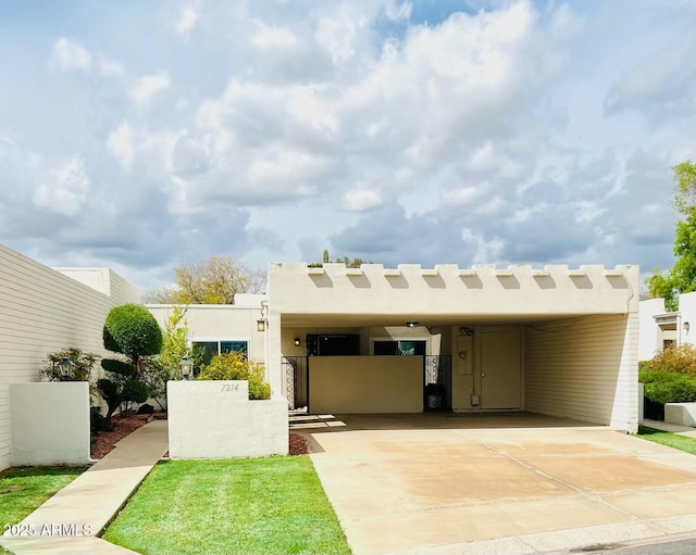 view of front of property with fence, stucco siding, an attached carport, a gate, and driveway
