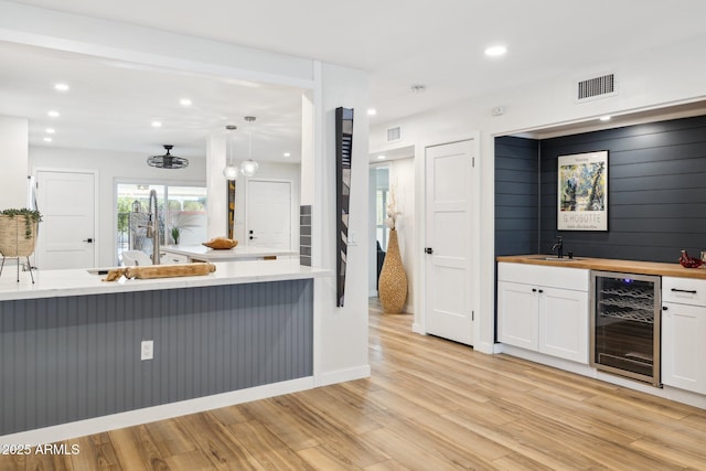 kitchen featuring visible vents, white cabinets, light wood finished floors, wine cooler, and recessed lighting