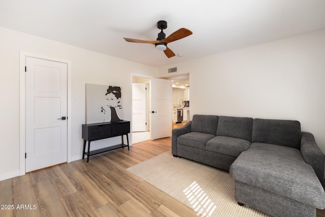 living room with visible vents, light wood finished floors, ceiling fan, and baseboards