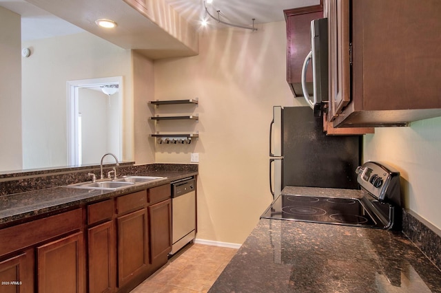 kitchen with dark stone counters, appliances with stainless steel finishes, light tile patterned flooring, and sink