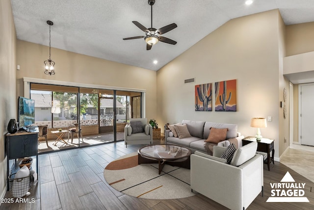 living room featuring a textured ceiling, high vaulted ceiling, and ceiling fan with notable chandelier