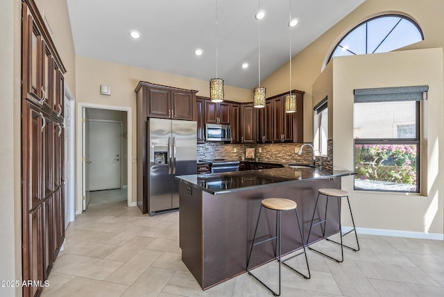 kitchen with dark stone countertops, appliances with stainless steel finishes, decorative backsplash, decorative light fixtures, and lofted ceiling