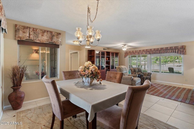 dining area with a textured ceiling, ceiling fan with notable chandelier, and light tile patterned flooring