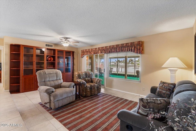 living room with a ceiling fan, a textured ceiling, tile patterned flooring, and visible vents