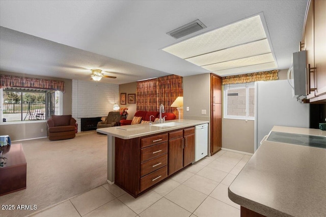 kitchen with visible vents, a sink, white appliances, a peninsula, and a fireplace