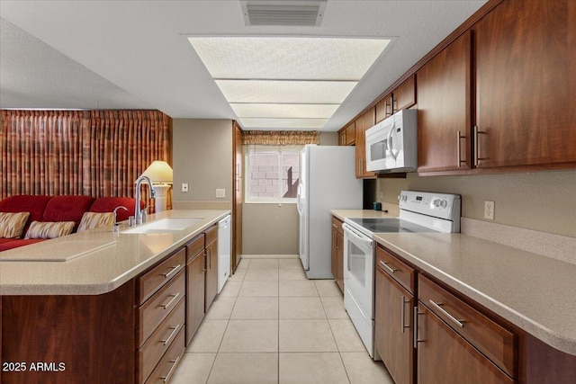 kitchen with white appliances, light tile patterned floors, a peninsula, visible vents, and a sink