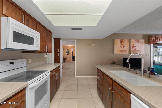 kitchen featuring light tile patterned floors, white appliances, light countertops, a sink, and baseboards
