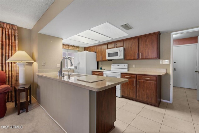 kitchen with visible vents, light tile patterned floors, light countertops, white appliances, and a peninsula