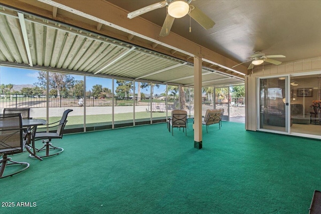 unfurnished sunroom featuring a ceiling fan and plenty of natural light