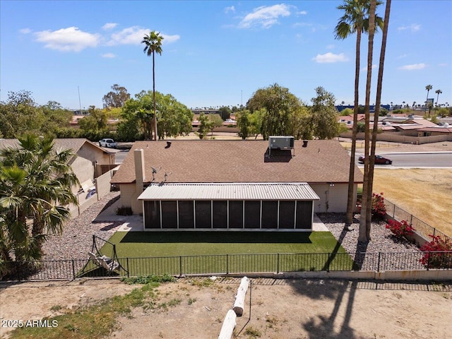 back of property featuring a fenced backyard, a sunroom, and a lawn