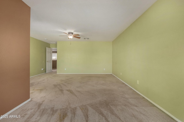 spare room featuring ceiling fan, light colored carpet, baseboards, and visible vents