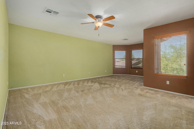 carpeted spare room with a ceiling fan, baseboards, and visible vents